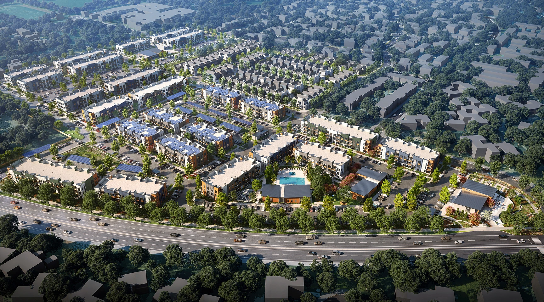 Aerial view of a large suburban housing development with rows of houses, roads, green spaces, and a main road in the foreground with moving vehicles.